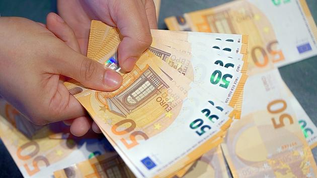 Χέρια με χαρτονομίσματα ευρώ